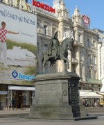Standbeeld op groot plein met erachter reklamebord